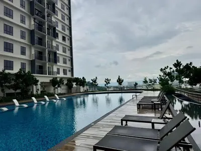 a swimming pool next to a building with lounge chairs at Simple Stay Aston Acacia Bukit Mertajam in Bukit Mertajam