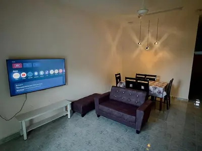 a living room with a couch and a tv on the wall at Cozy 4BR Homestay with 2 Baths Taman Seraya in Kulim