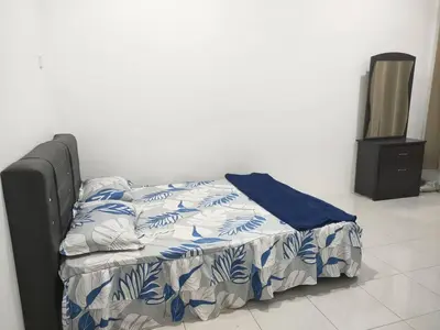 a bed with a blue and white comforter and a television at Hannan Homestay in Kuala Lipis