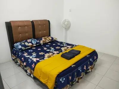 a bedroom with a bed with a yellow blanket and a fan at Hannan Homestay in Kuala Lipis