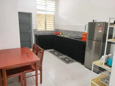 a kitchen with a table and a stainless steel refrigerator at Hannan Homestay in Kuala Lipis