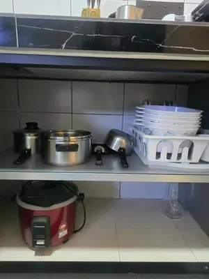a kitchen shelf with pots and pans and plates at The Highland Hive in Tanah Rata
