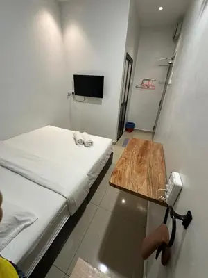 a small room with a bed and a wooden table at LM Motel in Kulim