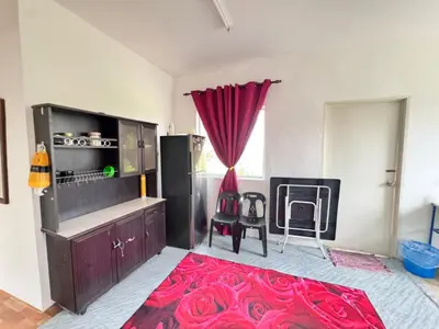a living room with a red rug and a kitchen at Homestay Tanah Liat in Bukit Mertajam