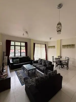 a living room with black couches and a table at Cameron Prima Villa Homestay in Tanah Rata