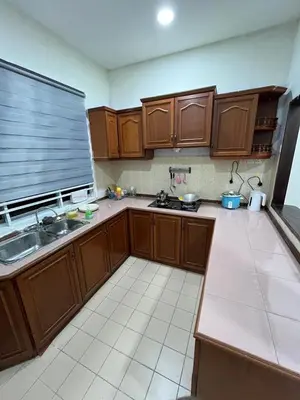 a kitchen with wooden cabinets and a sink and a counter at KMK Homestay in Sungai Petani