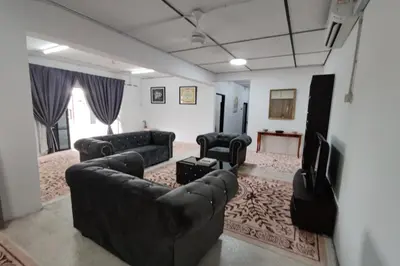 a living room with black leather couches and a television at DRH Villa in Ipoh