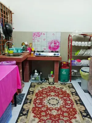 a kitchen with a table and a rug on the floor at Homestay Kak Kiah Taiping in Taiping