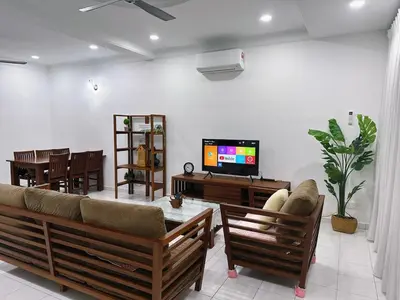 a living room with a couch and a tv and a table at Maple Home BM in Bukit Mertajam