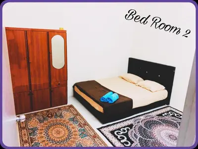 a bedroom with a bed and a dresser and rug at Nizaman's Homestay Gerik in Gerik