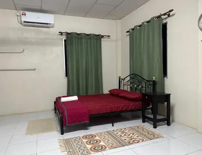 a bedroom with a bed with a table and green curtains at Homestay Teluk Bayu in Sungai Petani