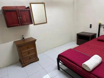 a bedroom with a bed and a dresser and a mirror at Homestay Teluk Bayu in Sungai Petani