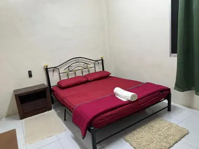 a bedroom with a bed with red sheets and a fireplace at Homestay Teluk Bayu in Sungai Petani