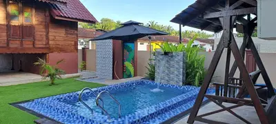 a swimming pool in a yard with an umbrella at Homestay Singgah Keluarga Warisan Abg Tam in Kepala Batas