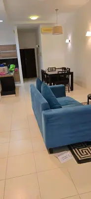 a blue couch in a living room with a table at Deluxe Apartment CintaSayang Resort in Sungai Petani