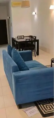 a blue couch in a living room with a table at Deluxe Apartment CintaSayang Resort in Sungai Petani