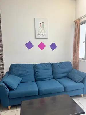 a blue couch in a living room with a picture on the wall at AYAAN Budget Homestay at Tanah Rata in Tanah Rata