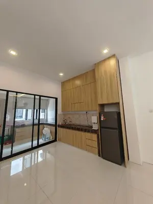 a kitchen with wooden cabinets and a black refrigerator at Ipoh M Villa 2 in Ipoh