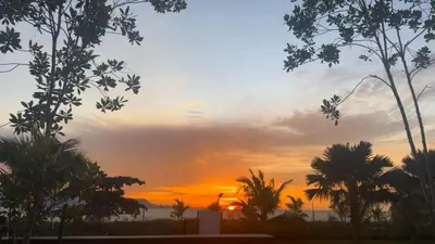 a sunset over the ocean with palm trees in the foreground at Seaview Master Room - Ensuite Bath in Butterworth in Butterworth