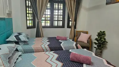 a bedroom with two beds and a chair and windows at Rumah Inap Haziq in Seri Manjung