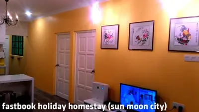 a room with a yellow wall with pictures on it at Fastbook Sun Moon City Home 12Pax in Ayer Itam