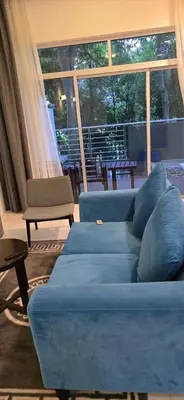 a living room with blue couches and a large window at Deluxe Apartment at CintaSayang Resort in Sungai Petani