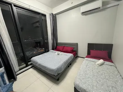 two beds in a room with a window at urban suites 3 bedroom 10pax a29 in Jelutong