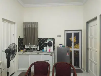 a kitchen with a refrigerator and chairs in a room at Teratak Desa Cemerlang 2 in Kuala Kangsar