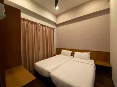 a bedroom with two beds with white sheets and a window at Nova Homestay Cameron Highlands in Brinchang