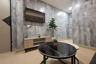 a living room with a table and a tv on a wall at The Cozy Hotel in Sungai Petani