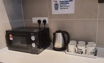 a microwave sitting on a kitchen counter with cups at ICC Suites Ipoh City Center, New & cozy, 6 Pax in Ipoh