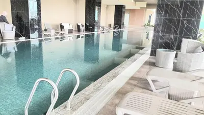 a large swimming pool with white chairs and tables at ICC Suites Ipoh City Center, New & cozy, 6 Pax in Ipoh
