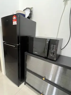 a microwave on a shelf next to a black refrigerator at Cozy Modern Condo with Pool & City Access in Bayan Lepas