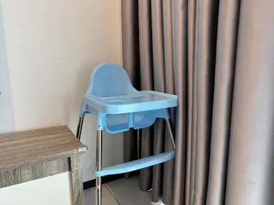 a blue high chair in front of a curtain at SeaView Premium Family Suite 3B2R in George Town