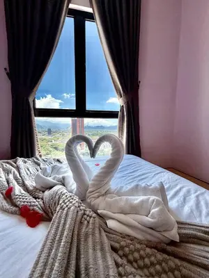 two swans making a heart on a bed with a window at The Horizon Ipoh Skyline by Grab A Stay in Ipoh