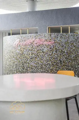 a white table with two orange chairs next to a tile wall at 22Macalisterz by MC Home in George Town
