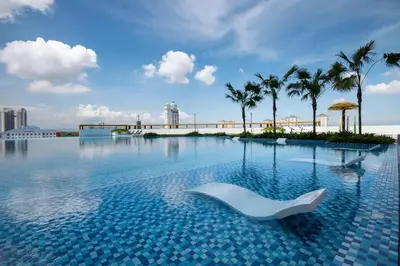 a swimming pool with a white chair in the water at Metropol by BRB in Bukit Mertajam