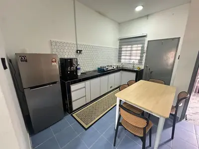 a kitchen with a table and a refrigerator at RJ Homestay Bandar Utama Gua Musang in Gua Musang