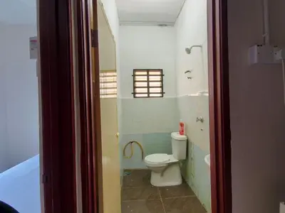 a bathroom with a toilet and a window and a tub at Nariz Homestay Kuala Ketil in Kuala Ketil