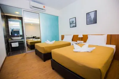 a hotel room with two beds and a mirror at Urban Inn Kulim in Kulim