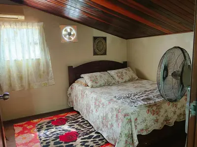 a bedroom with a bed with a fan and a rug at Homestay Bedong Teratak Kasih in Gua Sai