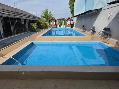a large swimming pool with blue water in front of a building at Homestay Tok Ani by Ardzman Hospitality in Permatang Pauh