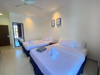 two beds in a hotel room with blue pillows at Mak Sa'adiah Hotel in Kampung Teluk Nipah
