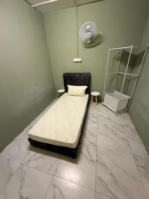 a small room with a bed and a fan at Rina Hostel in Ipoh
