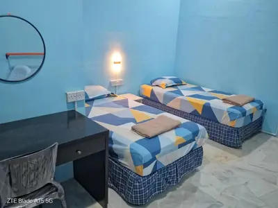 two beds in a room with a desk and a mirror at Shaja Homestay in Kampong Kepayang