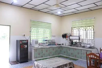 a kitchen with a refrigerator and a table in a room at Shaja Homestay in Kampong Kepayang