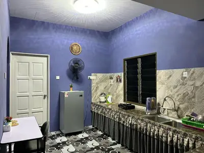 a kitchen with purple walls and a counter and a refrigerator at Homestay ABAH in Nibung Tebal