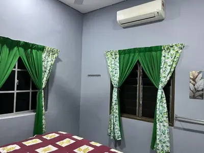 a bedroom with green curtains and a window at Homestay ABAH in Nibung Tebal