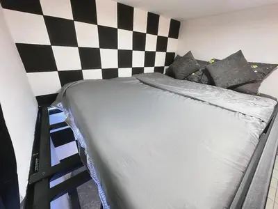 a bed in a room with a checkered wall at Unisuites Kampar Studio UTAR TARC -3pax, Pet Friendly, FREE 1 Carpark & Netflix in Kampar