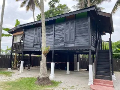 a black house with a porch and a tree at Rumah Inap Kampung Agong Sunrise in Penaga